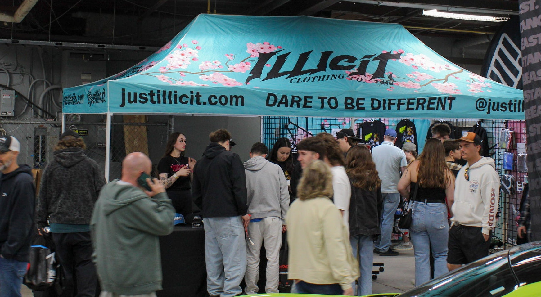 Event with a branded tent and people around, featuring illicit clothing co branding.